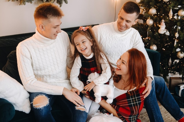 Portrait en gros plan d'une famille heureuse assise sur un canapé près d'un arbre de Noël célébrant des vacances.