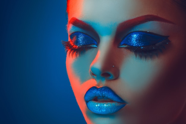 Portrait en gros plan d'une femme adulte aux yeux fermés en lumières rouges et bleues en studio