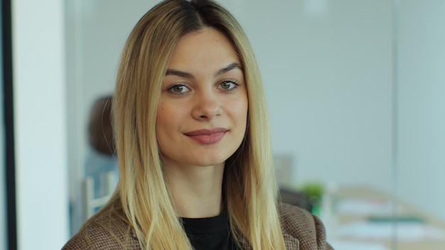 Portrait en gros plan d'une femme d'affaires heureuse et prospère, femme d'affaires du millénaire posant au bureau avec un arrière-plan flou d'équipe