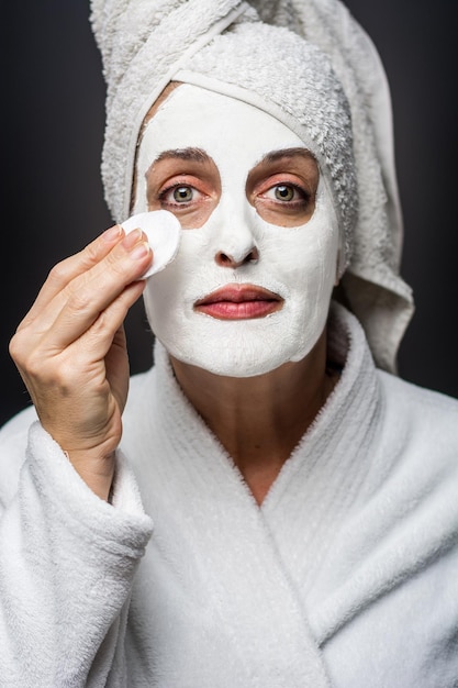 Photo portrait en gros plan d'une femme appliquant un masque facial sur un fond noir