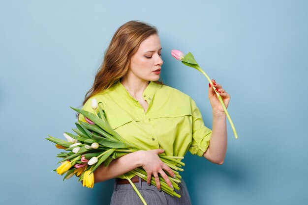 portrait en gros plan d'une femme avec un bouquet de fleurs de tulipes sur un fond bleu propre concept de félicitations
