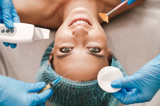 Photo portrait en gros plan d'une femme caucasienne heureuse recevant une procédure cosmétique et une injection en position couchée dans un salon de beauté