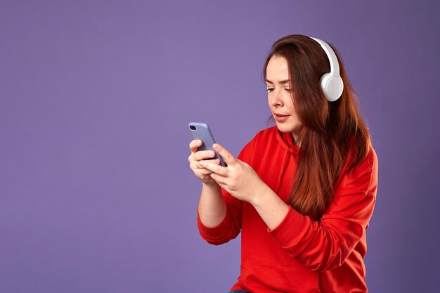 Portrait en gros plan d'une femme caucasienne en podcast ou en écoute de musique sur fond violet Femme écoutant de la musique dans des écouteurs