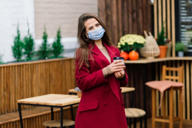 Portrait en gros plan d'une femme caucasienne portant un masque médical et debout dans la rue et le café