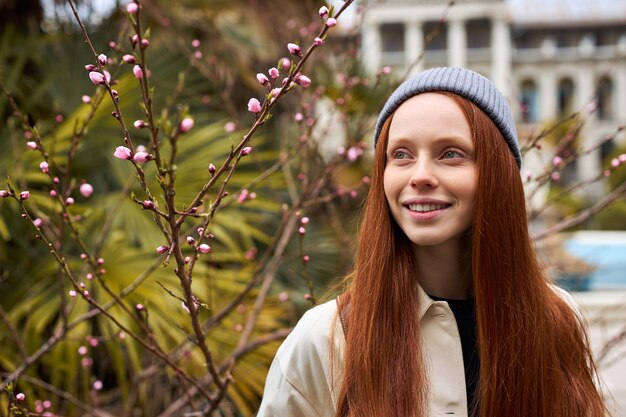 Portrait en gros plan d'une femme dans un jardin de printemps, une femme rousse à la mode au printemps aime sentir l'odeur de b...