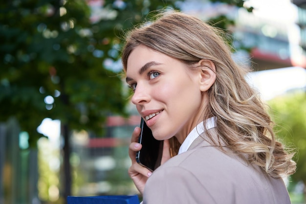 Portrait en gros plan d'une femme d'entreprise appelant sur un téléphone portable marchant dans la rue avec des documents de travail je