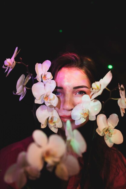 Photo portrait en gros plan d'une femme avec des fleurs roses sur un fond noir