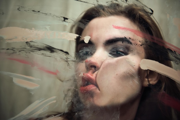 Portrait en gros plan d'une femme pressant son visage sur une fenêtre en verre