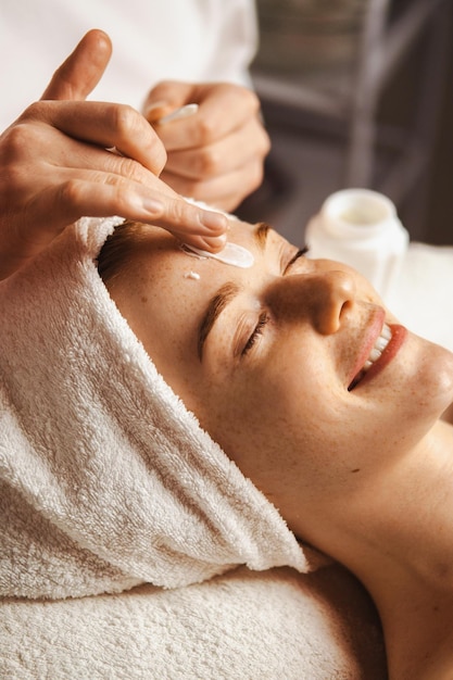 Photo portrait en gros plan d'une femme recevant un traitement de massage facial au spa avec une crème hydratante au salon de beauté