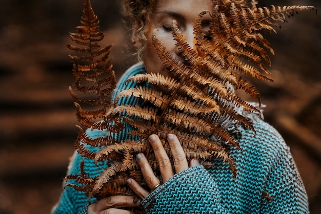 Portrait en gros plan d'une femme sentant la nature tenant une grande feuille brune d'automne sec dans la forêt tropicale. Concept de personnes et d'environnement. Sauvez la planète et la célébration du jour de la terre