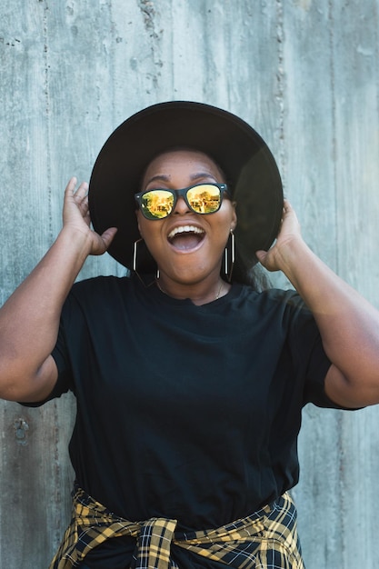 Portrait en gros plan d'une fille afro-américaine amusante et élégante aux cheveux bouclés portant des lunettes de soleil à la mode sur des photos urbaines d'été hipster avec un style instagram