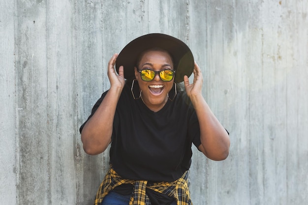 Portrait en gros plan d'une fille afro-américaine amusante et élégante aux cheveux bouclés portant des lunettes de soleil à la mode sur des photos urbaines d'été hipster avec un style instagram