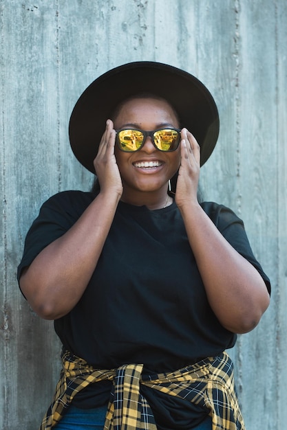 Portrait en gros plan d'une fille afro-américaine amusante et élégante aux cheveux bouclés portant des lunettes de soleil à la mode sur des photos urbaines d'été hipster avec un style instagram