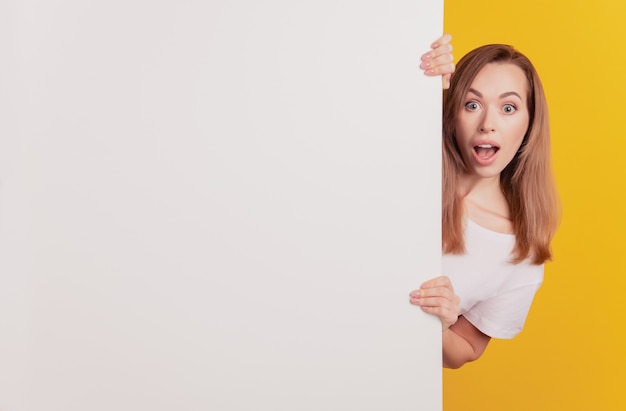 Portrait en gros plan d'une fille de conseiller surprise, bouche ouverte, tenir un panneau d'affichage blanc