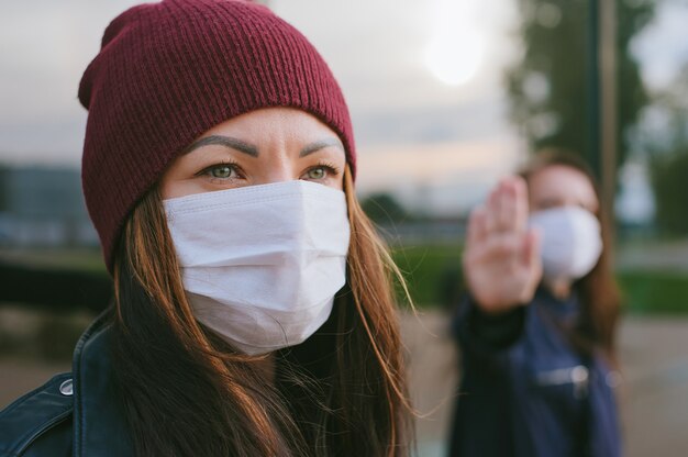 Portrait en gros plan d'une fille avec un masque médical sur le fond d'une autre fille.