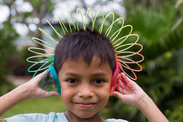 Photo portrait en gros plan d'un garçon souriant avec un jouet en spirale coloré dans un parc