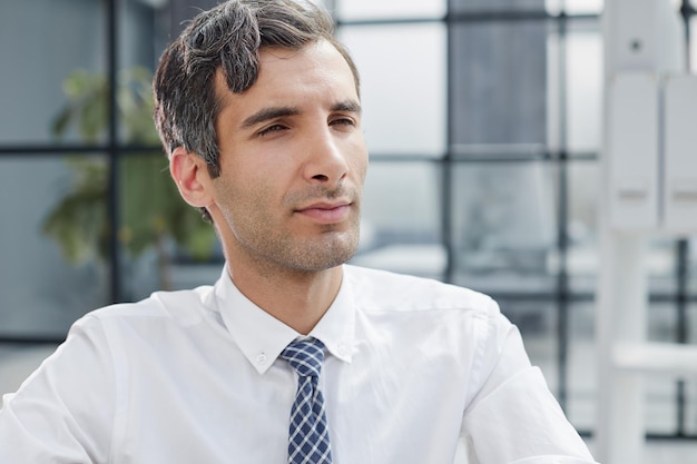 Portrait en gros plan d'un homme d'affaires concentré sérieux portant une chemise blanche regardant la caméra