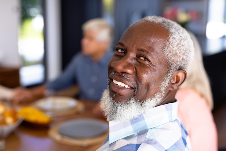Photo portrait en gros plan d'un homme âgé afro-américain avec des amis multiraciaux assis à la table à manger. heureux, barbe, inchangé, amitié, convivialité, soutien, vie assistée et concept de retraite.