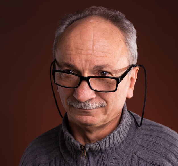 Portrait en gros plan d'un homme âgé portant des lunettes avec une expression déformée et sceptique sur son visage