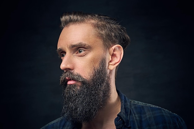 Portrait en gros plan d'un homme barbu aux cheveux longs sur fond sombre.