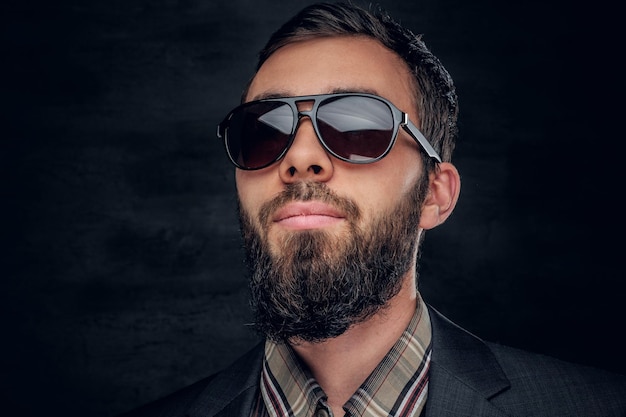 Portrait en gros plan d'un homme barbu en lunettes de soleil isolé sur fond gris vignette.