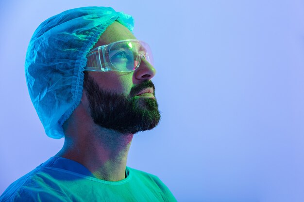 Portrait en gros plan d'un homme confiant scientifique portant unifrom et lunettes debout isolé sur une brume bleu-rose, levant les yeux