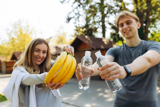 Portrait en gros plan d'un homme et d'une fille en bonne santé tenant des bananes et de l'eau