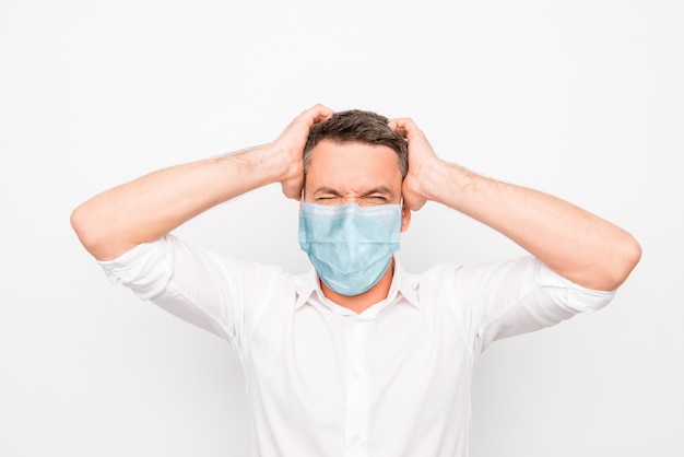 Portrait en gros plan d'un homme fou maléfique en colère portant un masque de gaze bleu maladie maladie maladie panique contamination isolée sur fond de couleur blanc clair