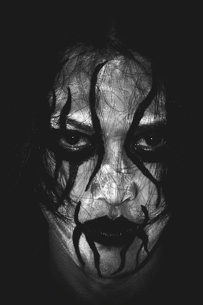 Portrait en gros plan d'un homme avec la peinture du visage dans la chambre noire