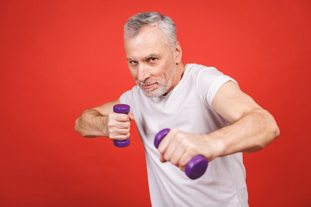 Portrait de gros plan d'un homme senior exerçant avec des haltères.