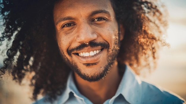 Portrait en gros plan d'un jeune adulte heureux avec des cheveux afro et un anneau de nez perforant posant pour la caméra beau homme noir multiethnique souriant couleur chaude modifier