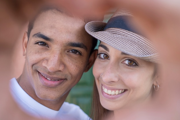 Portrait en gros plan d'un jeune couple multiethnique heureux souriant et faisant un soupir de foyer avec leurs mains ensemble - personnes interraciales d'amour et d'amitié - relation garçon et fille