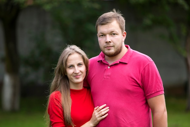 Portrait de gros plan de jeune couple souriant romantique heureux attrayant amoureux, jolie fille aux cheveux longs blonde et bel homme non rasé à l'extérieur sur fond rural d'été ensoleillé flou lumineux.