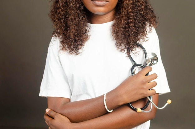 Portrait en gros plan d'une jeune femme africaine tenant un stéthoscope médical