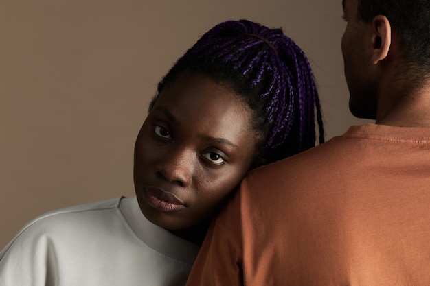 Portrait en gros plan d'une jeune femme afro-américaine regardant la caméra tout en s'appuyant sur son petit ami sur fond beige, espace pour copie