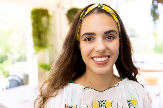 Portrait en gros plan d'une jeune femme biraciale souriante portant un bandeau jaune à la maison, espace de copie. Inaltéré, style de vie, beau, heureux et concept de maison.