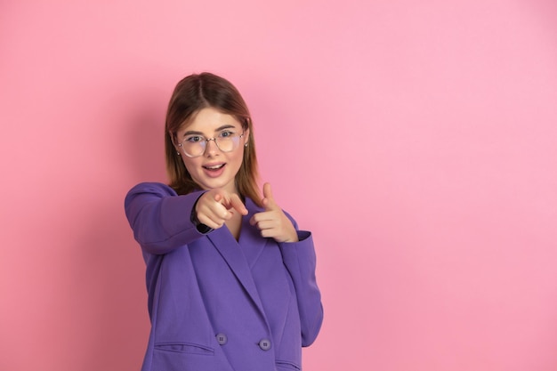 Portrait en gros plan d'une jeune femme caucasienne sur fond de studio rose, émotionnel et expressif