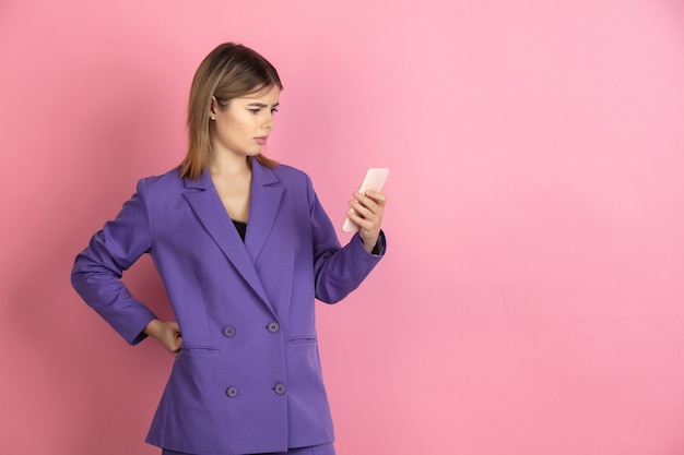 Portrait en gros plan d'une jeune femme caucasienne sur un studio rose, émotionnel et expressif