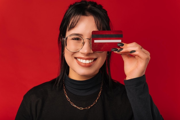 Portrait en gros plan d'une jeune femme couvrant un œil avec une carte de crédit