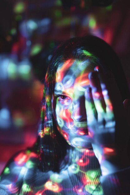 Photo portrait en gros plan d'une jeune femme couvrant le visage avec la main dans une pièce éclairée la nuit