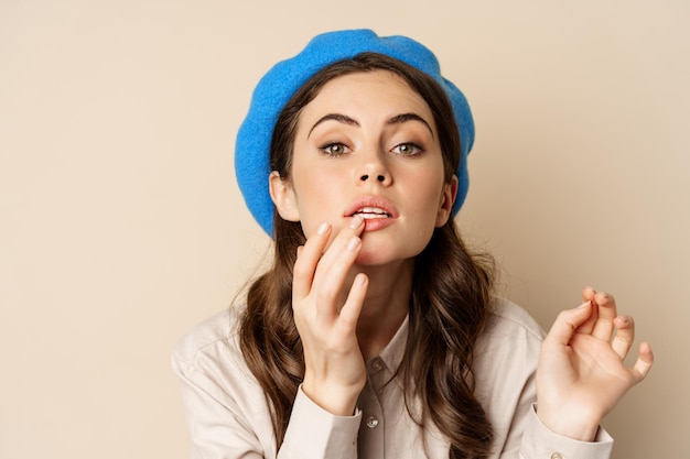 Portrait en gros plan d'une jeune femme magnifique regardant dans le miroir et fixant son maquillage mis sur le rouge à lèvres s...