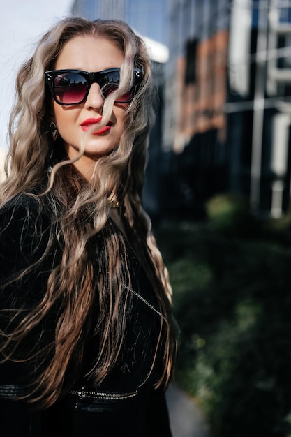 Portrait en gros plan d'une jeune femme à la mode en veste noire posant dans la rue