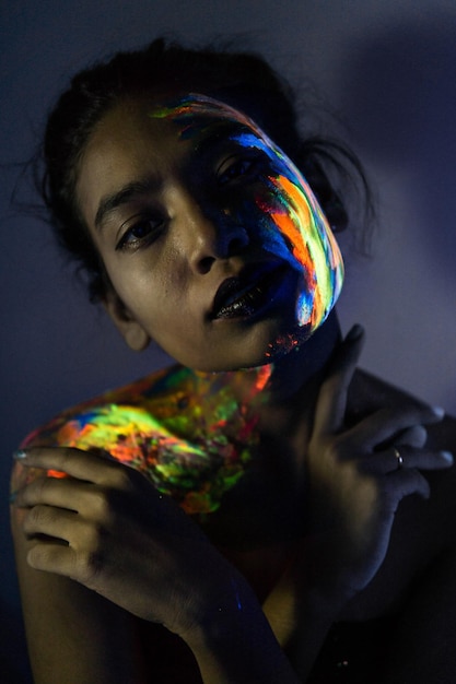 Portrait en gros plan d'une jeune femme avec la peinture du visage dans la chambre noire