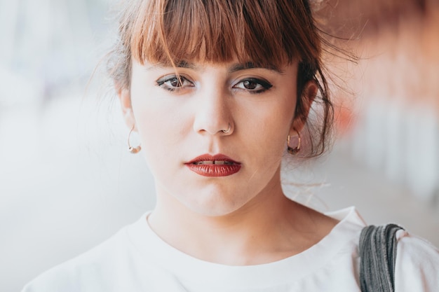 Portrait en gros plan d'une jeune femme regardant directement la caméra avec un visage sérieux et des lèvres rouges, maquillage sur les yeux, image conceptuelle hipster, jeunes