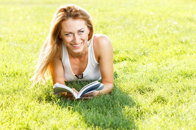 Portrait en gros plan d'une jeune femme séduisante allongée sur l'herbe verte dans un parc pendant l'été et écoutant de la musique avec ses écouteurs pensifs à l'extérieur