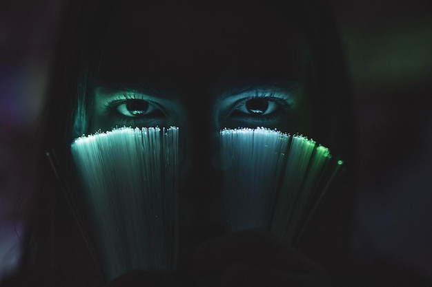 Portrait en gros plan d'une jeune femme tenant une fibre optique éclairée