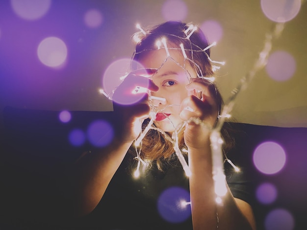 Portrait en gros plan d'une jeune femme tenant des lumières éclairées