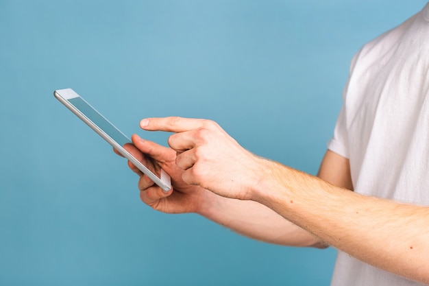 Portrait en gros plan d'un jeune homme aux cheveux roux barbu et heureux en utilisant une tablette et en se tenant debout