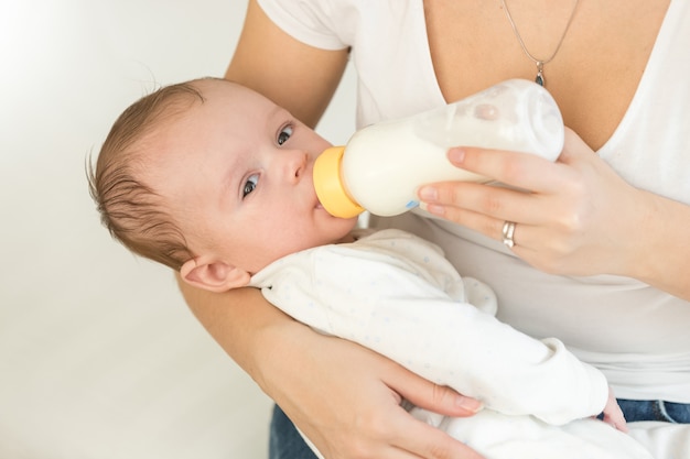 Portrait en gros plan d'une jeune mère tenant son petit garçon et se nourrissant de lait