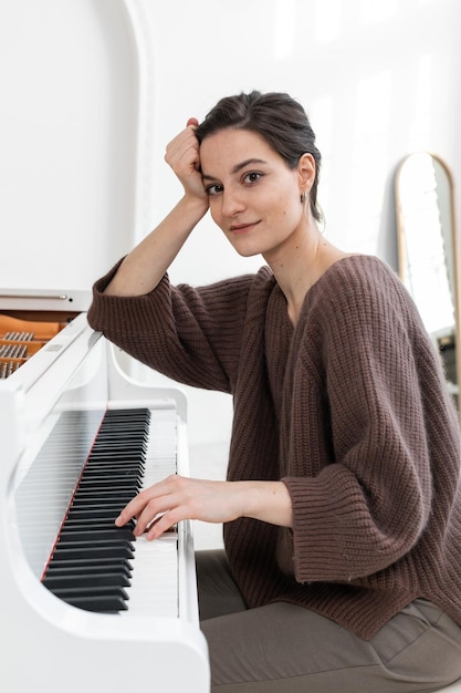 Un portrait en gros plan d'une jeune musicienne dans des vêtements décontractés élégants jouant du piano à queue